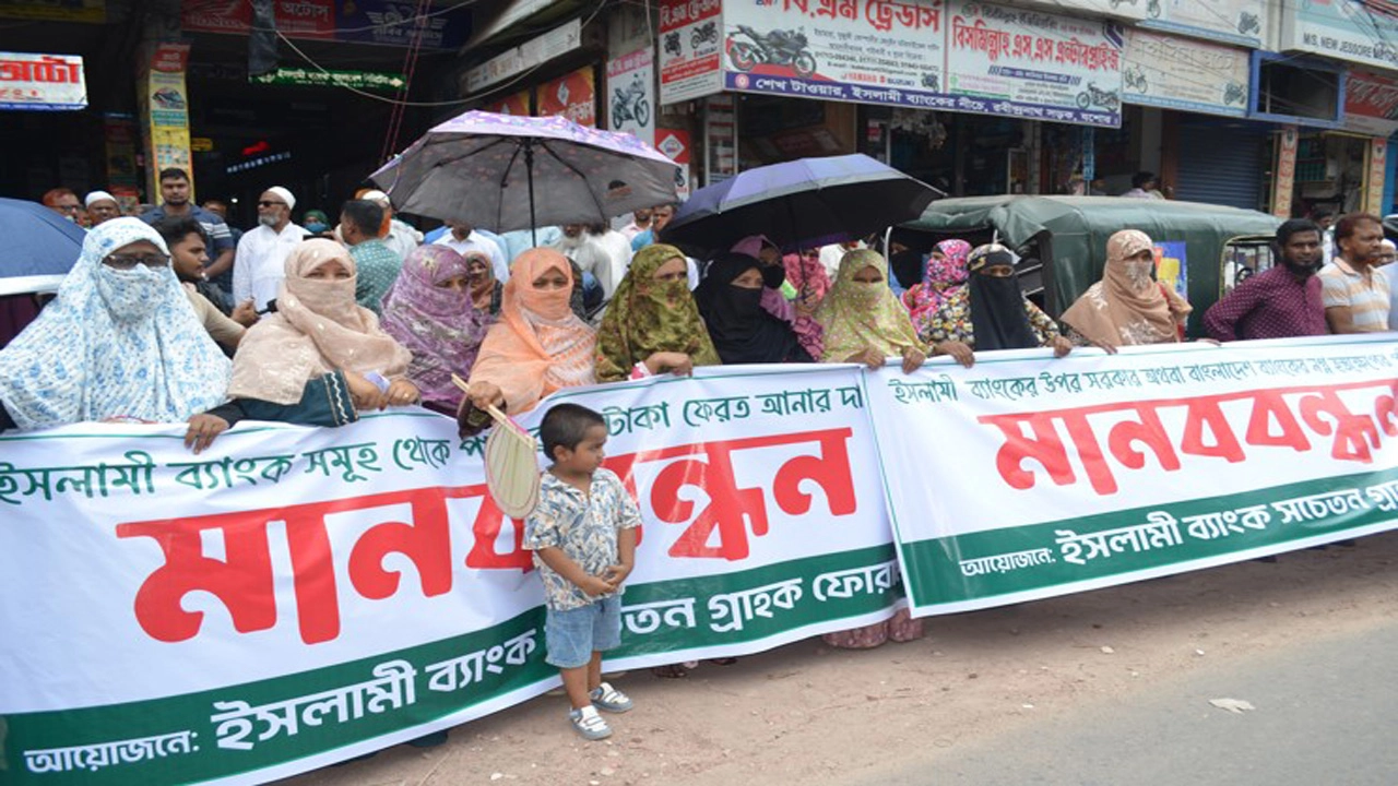 ইসলামী ব্যাংকিং ধ্বংসের ষড়যন্ত্রের প্রতিবাদে যশোর আরএন ব্যাংকের সামনে ইসলামী ব্যাংক সচেতন গ্রাহক ফোরামের উদ্যোগে মানববন্ধন অনুষ্ঠিত হয়েছে। ছবি: গ্রামের কাগজ